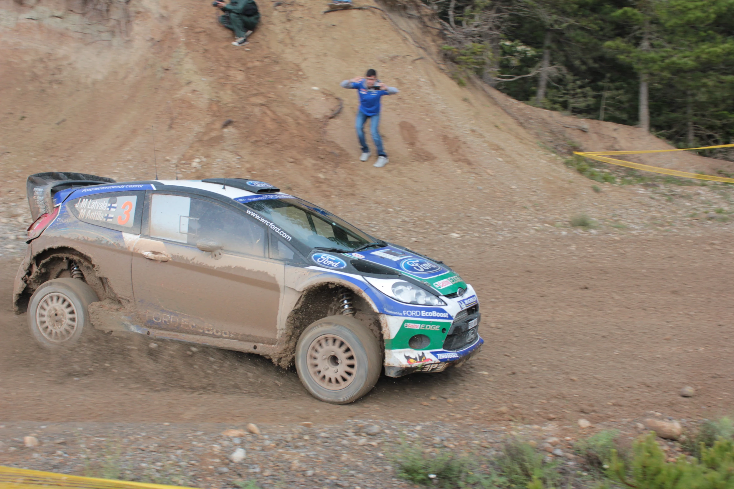 two people jumping off of a dirt hill on a small vehicle