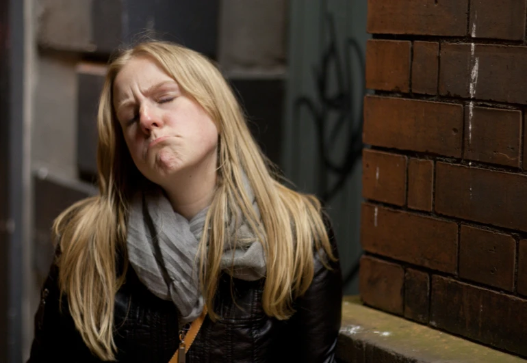 a woman is standing in front of a brick wall