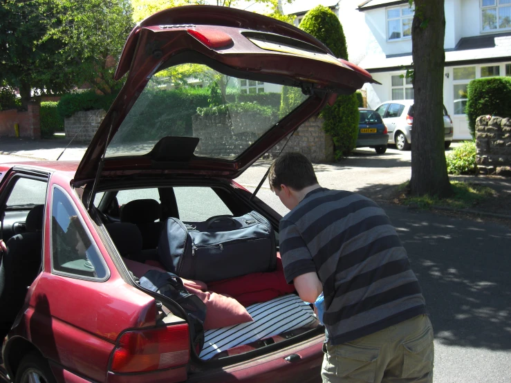 a man packing luggage into the trunk of a car