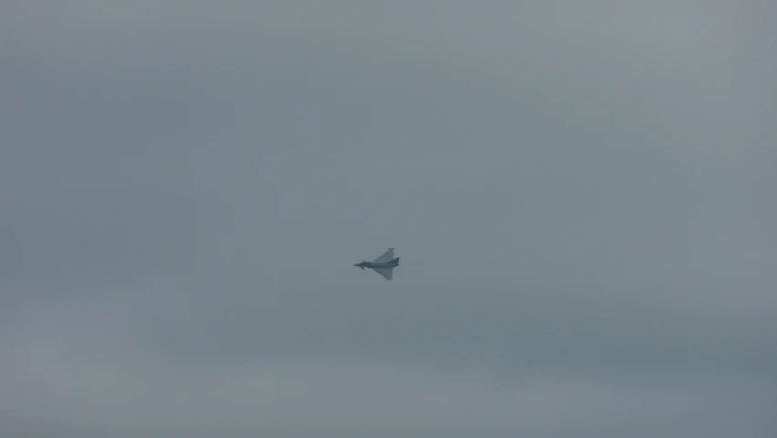a small jet flying through the sky on a foggy day