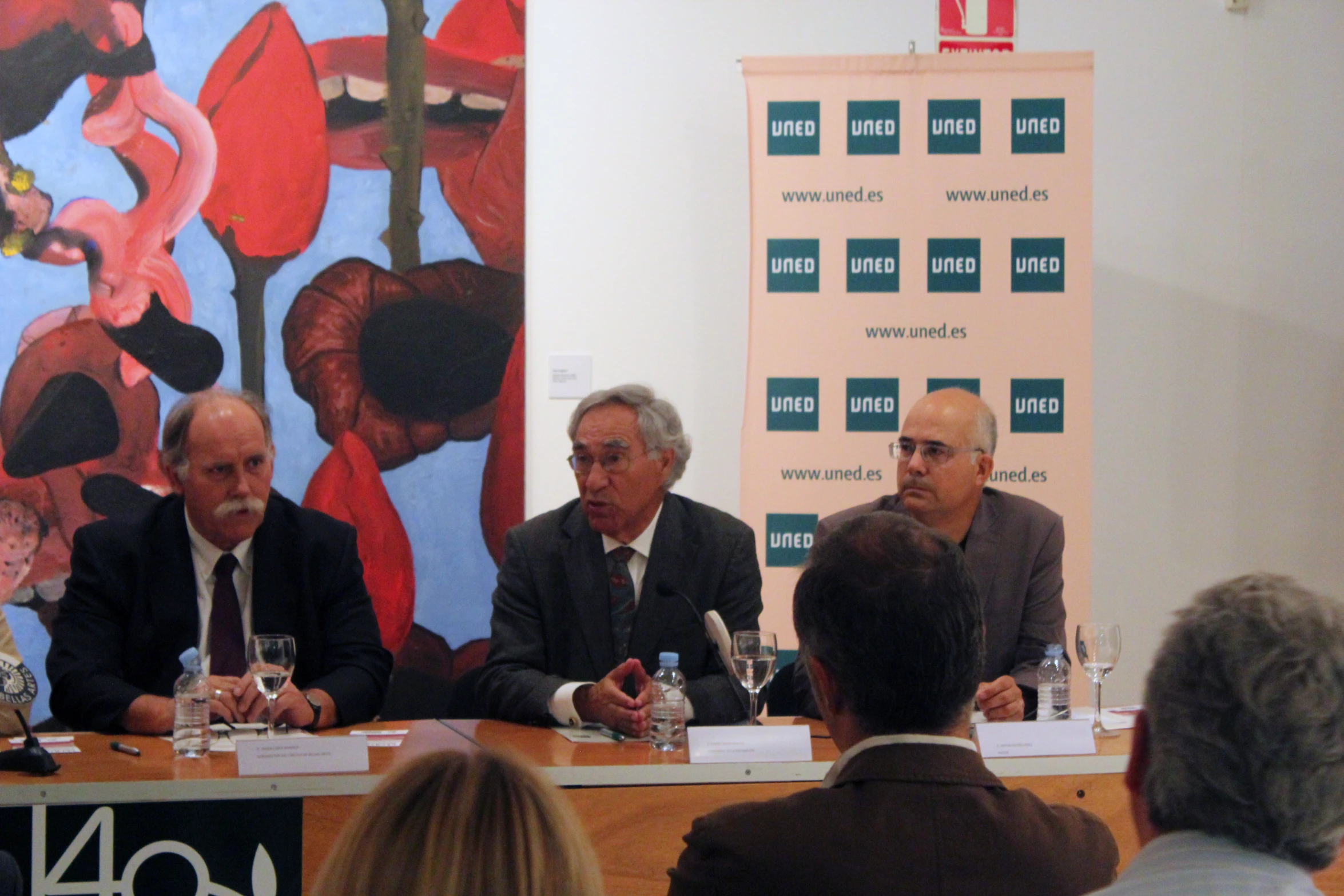 men sitting at a table speaking during a presentation