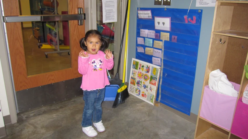 a little girl standing in front of a bulletin board