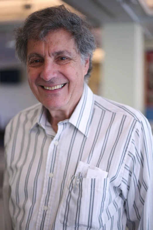 a smiling man wearing a white and blue striped shirt
