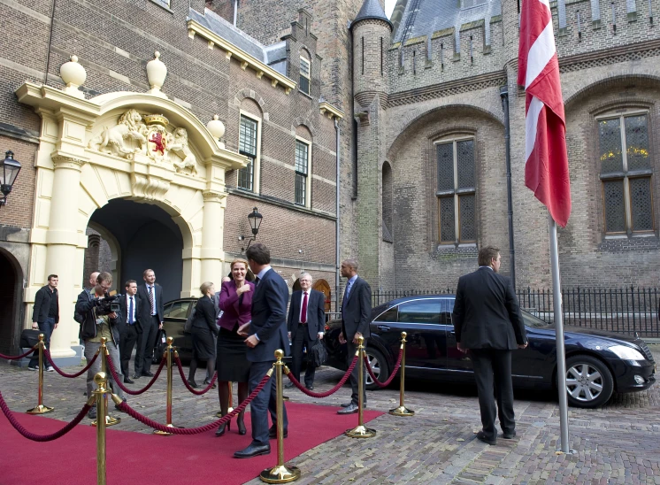 several people are lined up for a ceremony outside of a castle