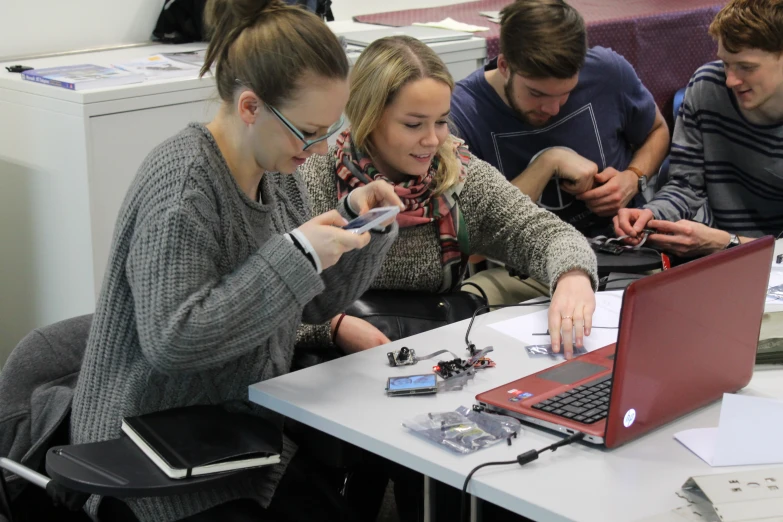 a group of people with cellphones and a laptop on a table