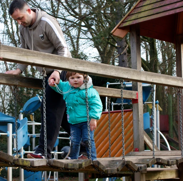 a child stands on the playground, and plays with his father