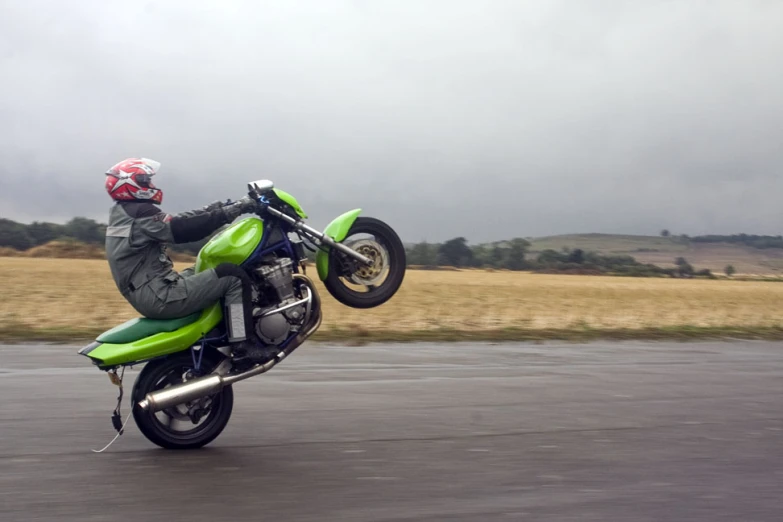 a motorcyclist is doing stunts in a cloudy scene