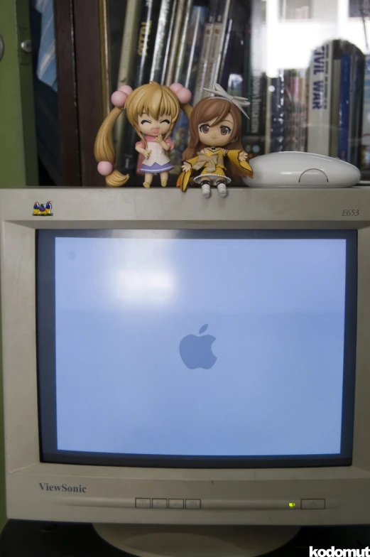 two dolls are sitting on top of a television