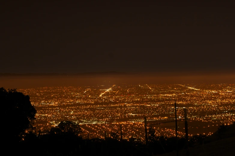 a view from the top of a hill looking down at a city and a tree lined hillside