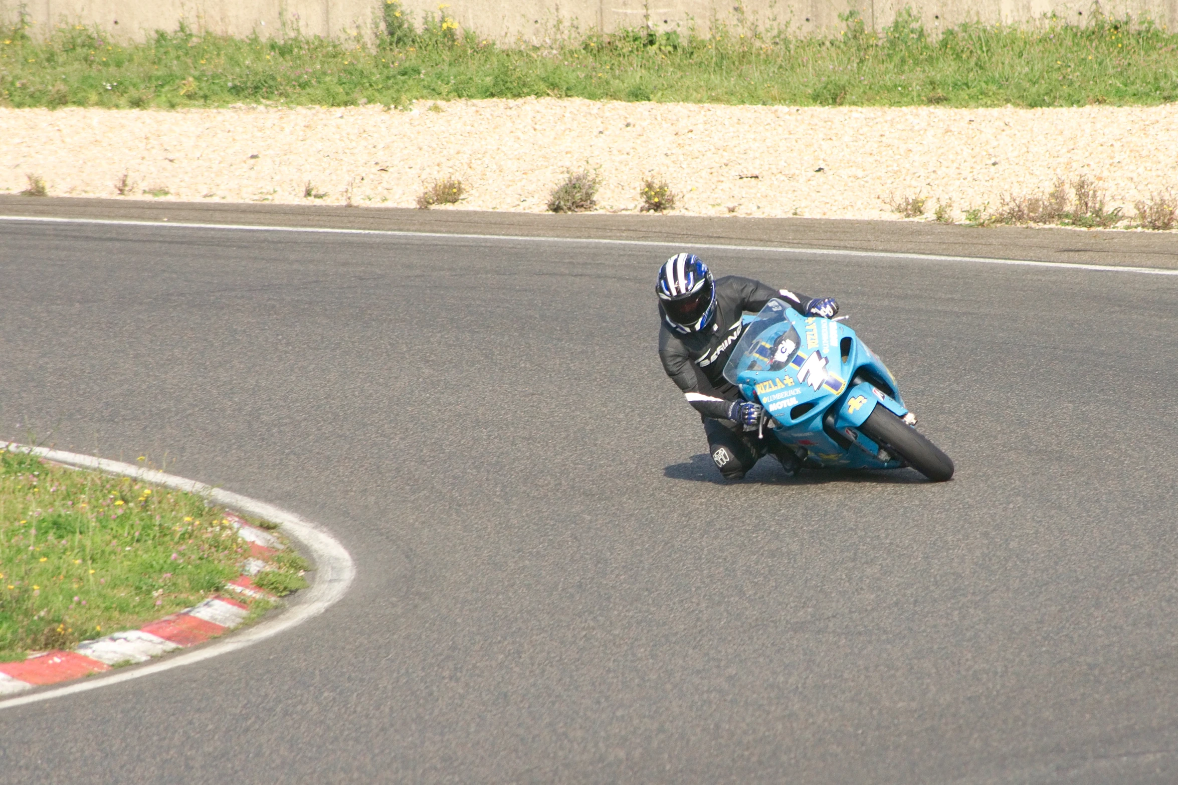 a person on a blue motorcycle rides down the track