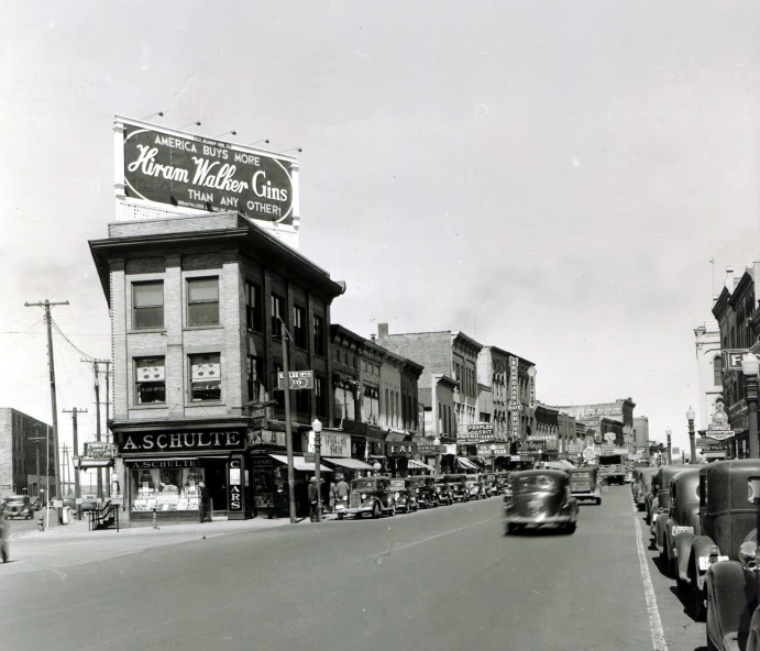 a busy road with lots of old cars driving past buildings