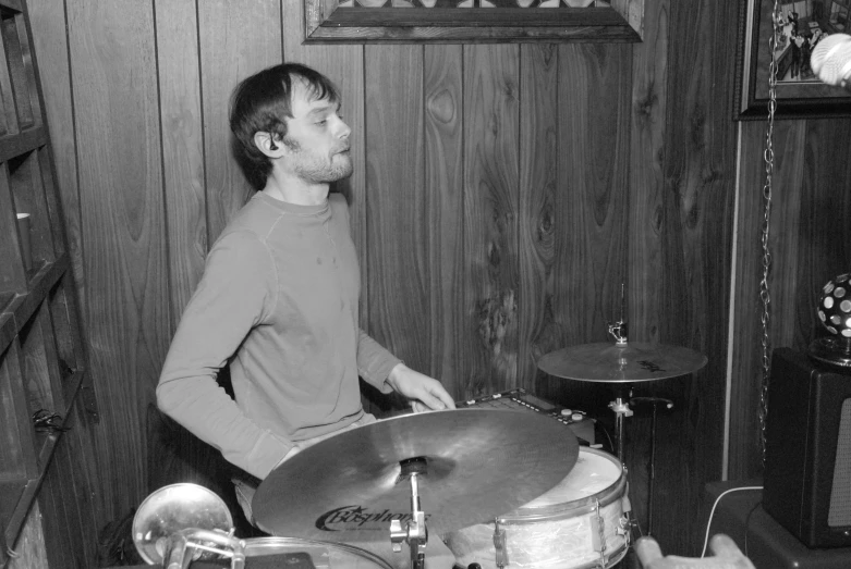 a young man is standing behind a drum set