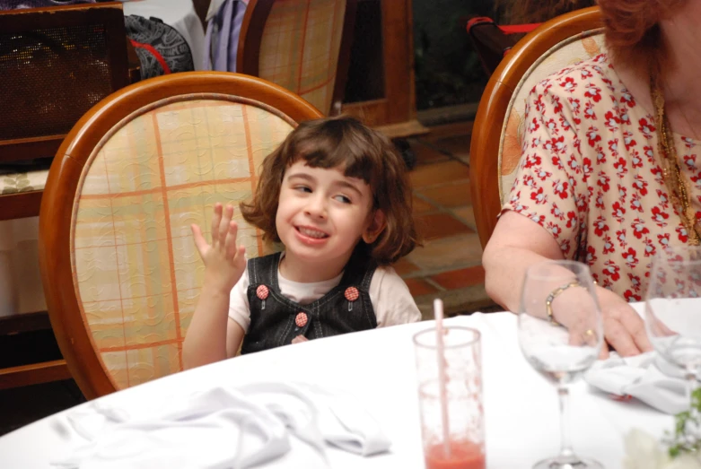 a little girl at the table making an odd face