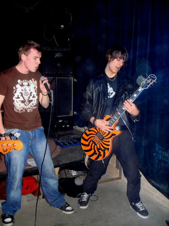 two male musicians playing guitars together and singing