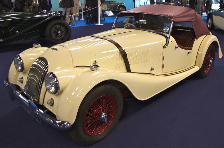 an old fashioned yellow sports car sitting on display