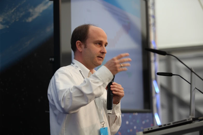 a man wearing white is giving a speech