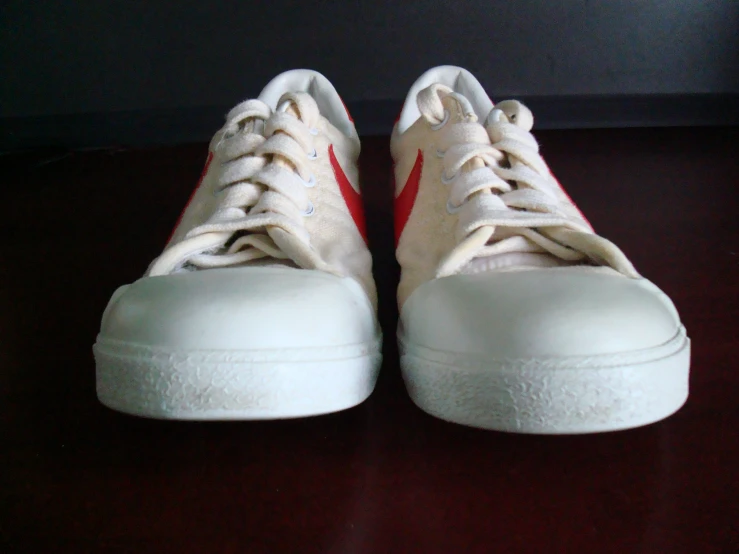 a pair of sneakers sitting on top of a dark brown floor