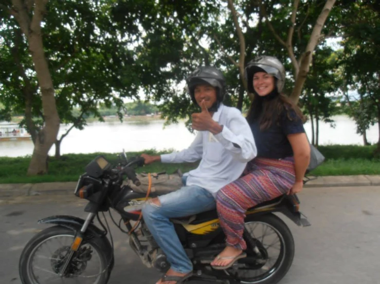 a man and woman riding on the back of a motorcycle