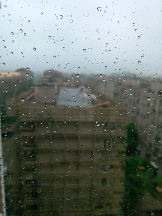 a view of buildings through a rain soaked window