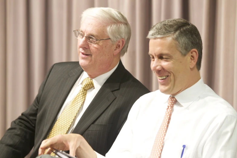 two men with glasses on one side and another man wearing a tie, both smiling, standing together