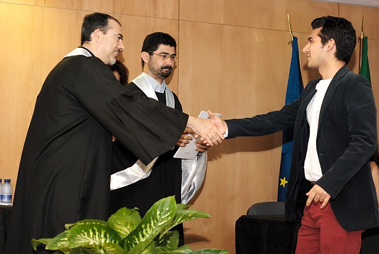 two men are shaking hands in front of a room