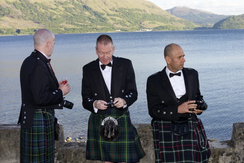 the three men are wearing kilts standing close to one another