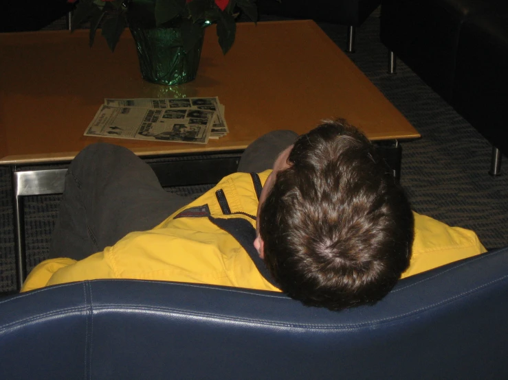 a man in a yellow jacket sitting on a blue leather couch