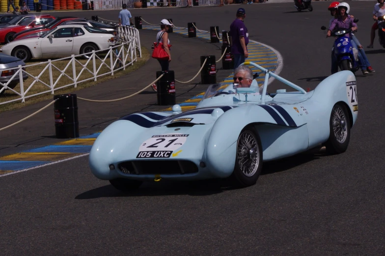 a old man driving a race car down the street