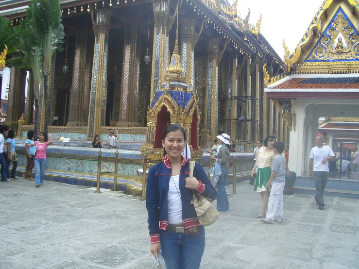 a woman standing in front of a building decorated with large golden pillars