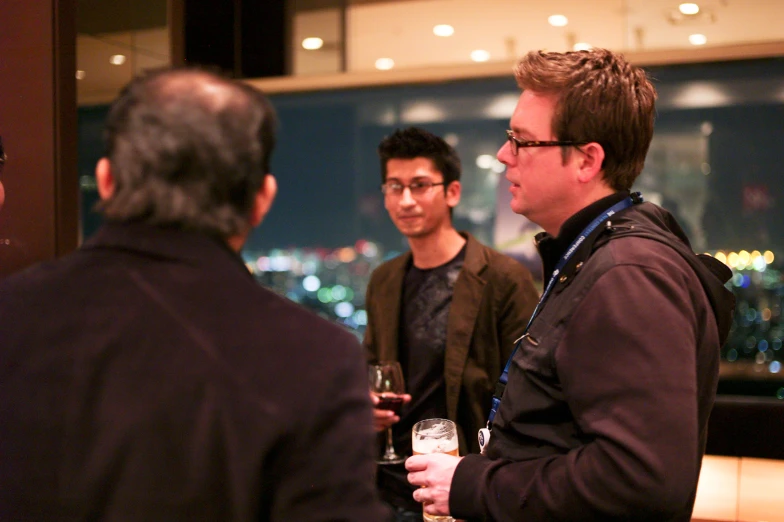 two men standing next to each other and drinking