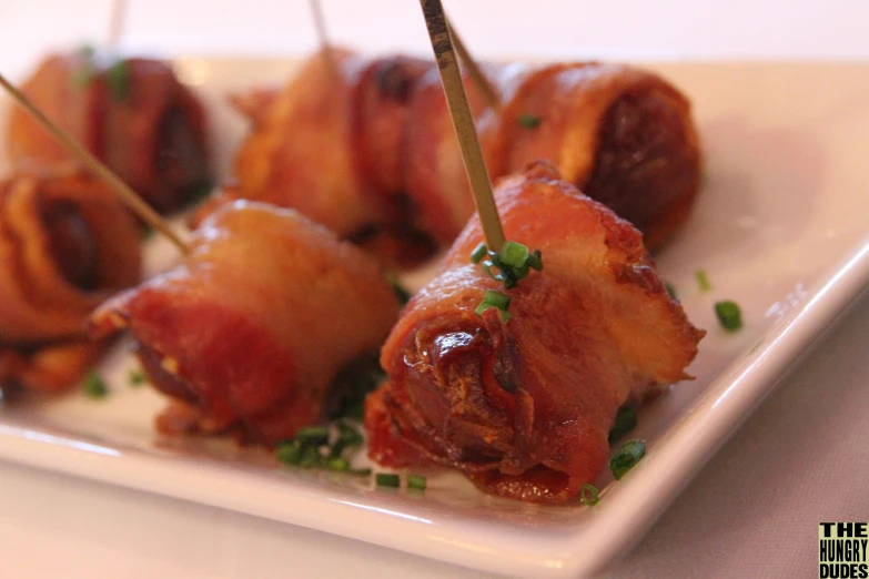 bacon wrapped skewers on a plate with tooth picks