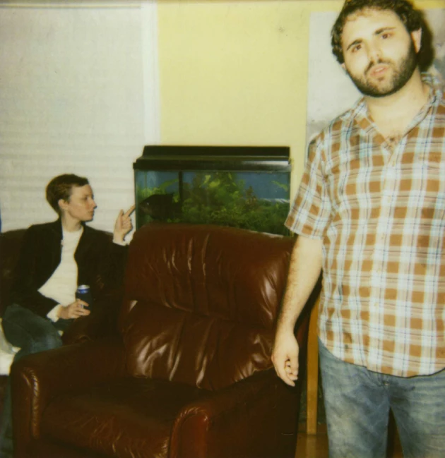 two people standing in a living room with a couch and table