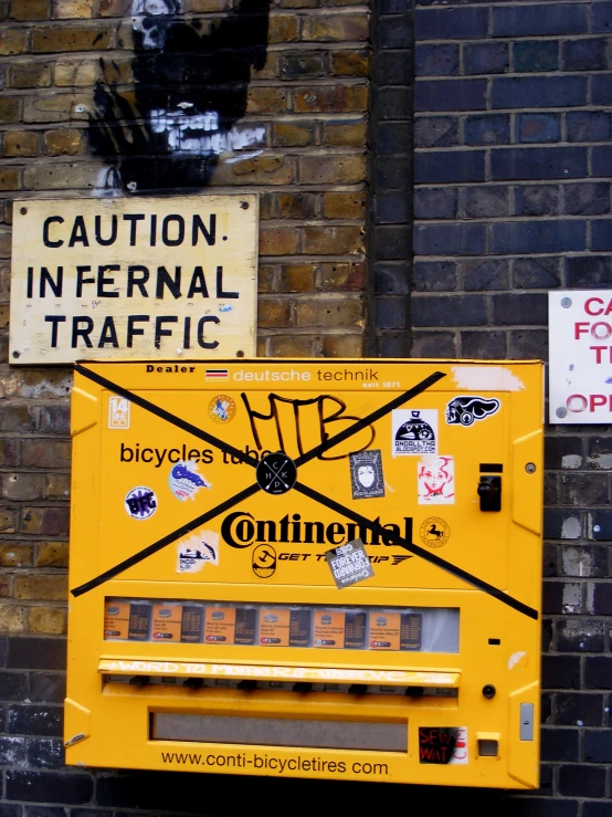 a street sign on a brick wall, with a caution sign in the background