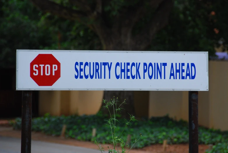 a security check point sign next to some greenery