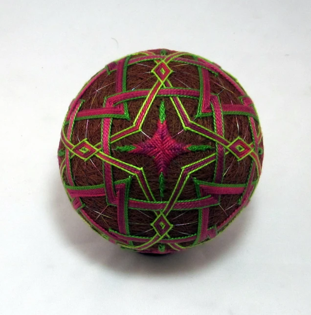 a brown, pink and green ball with decorative shapes on it