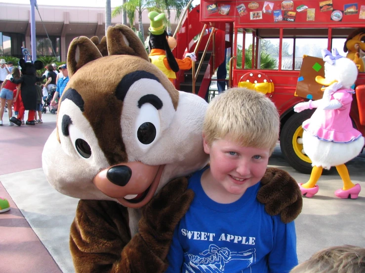 the boy is posing with a large mascot in a park
