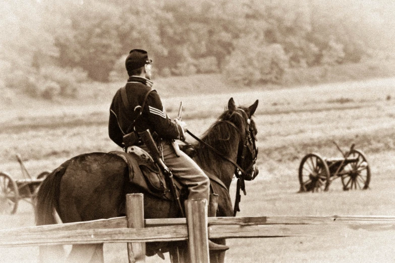 a man sitting on a horse near a fence