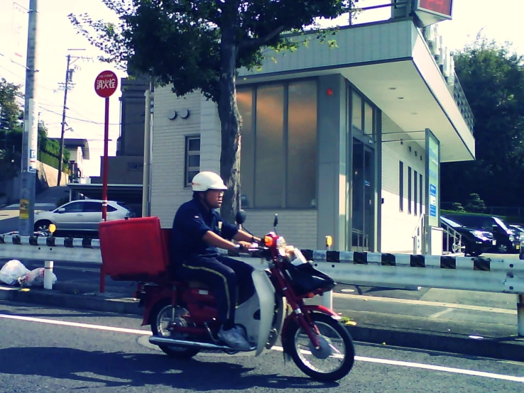 a man riding a motorcycle on the road with a large object in his back