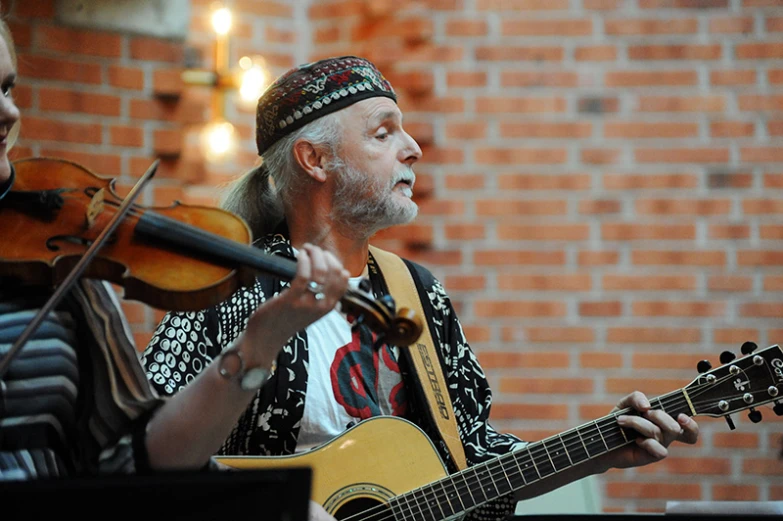 an older man playing guitar next to a young man playing the violin