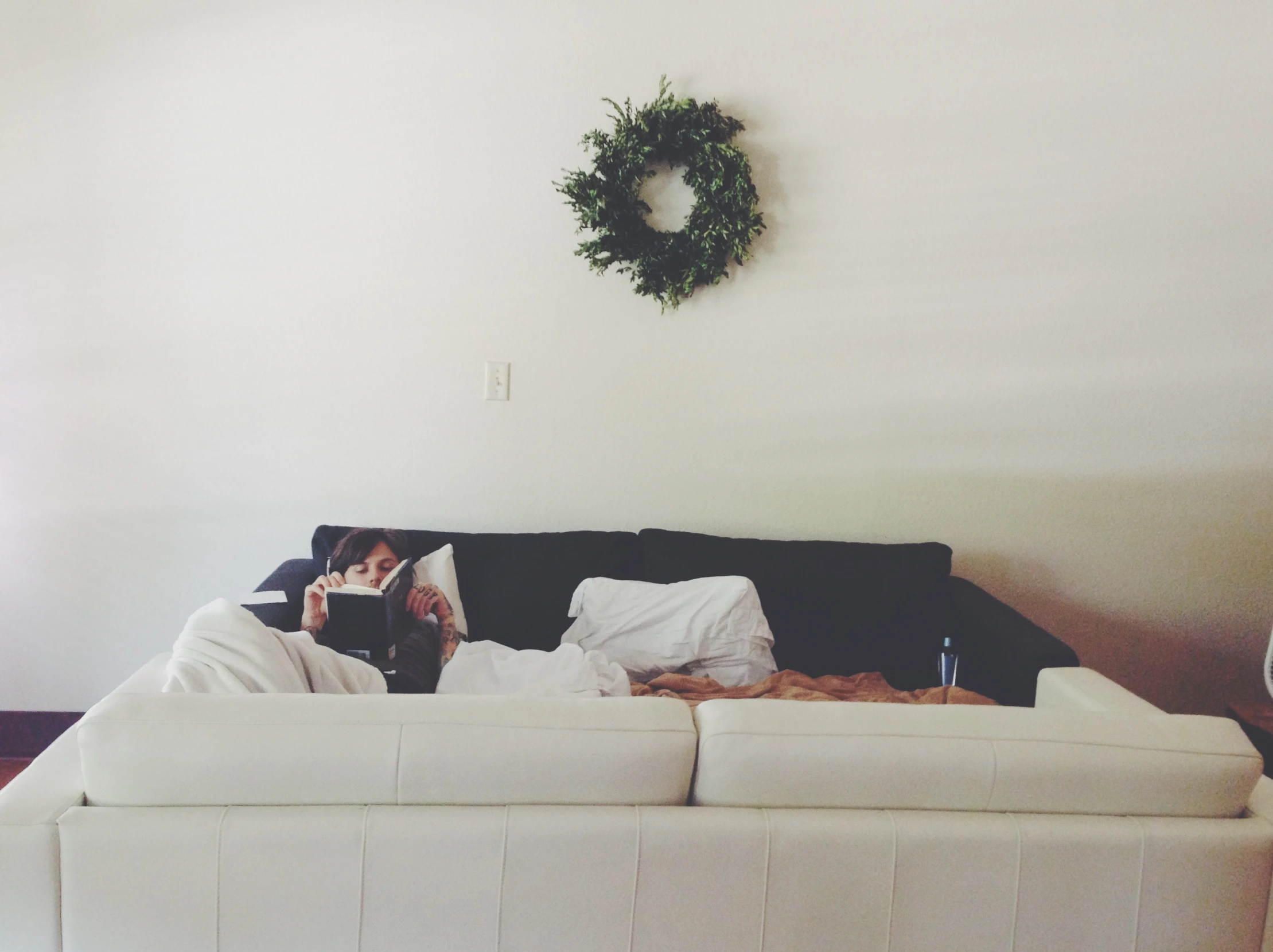 a woman sitting on top of a couch with her head covered by a blanket