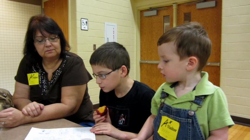 young children working on a project while an adult woman looks on