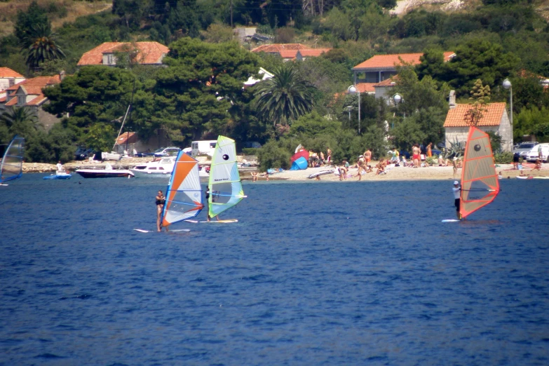 two windsurfers are riding in the ocean near buildings