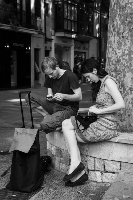 a woman sitting next to a man using a smart phone