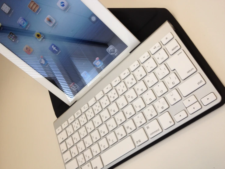 a white computer keyboard sitting next to an ipad