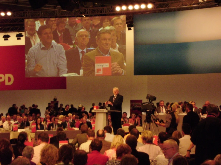 a man standing at a podium in front of a crowd of people