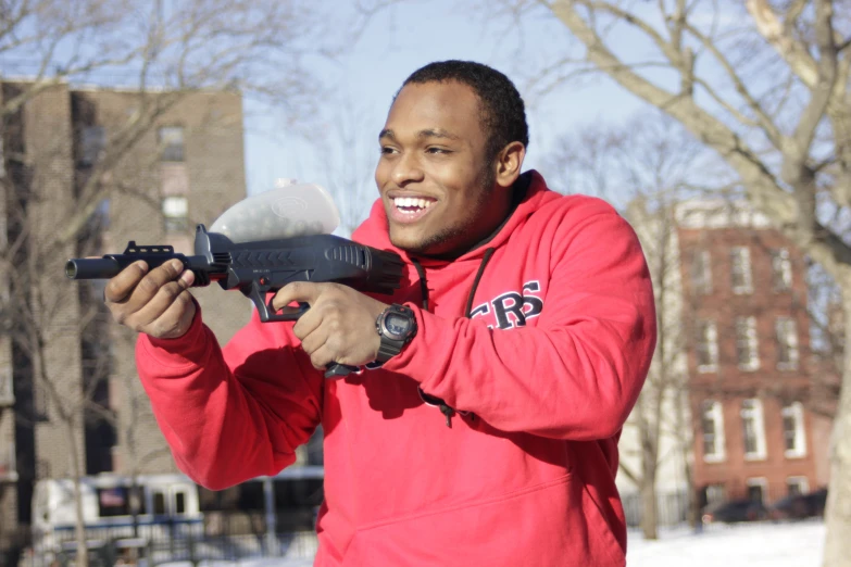 a man wearing a red hoodie holds an arg rifle