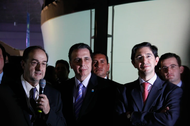 several men in suits are standing with microphones