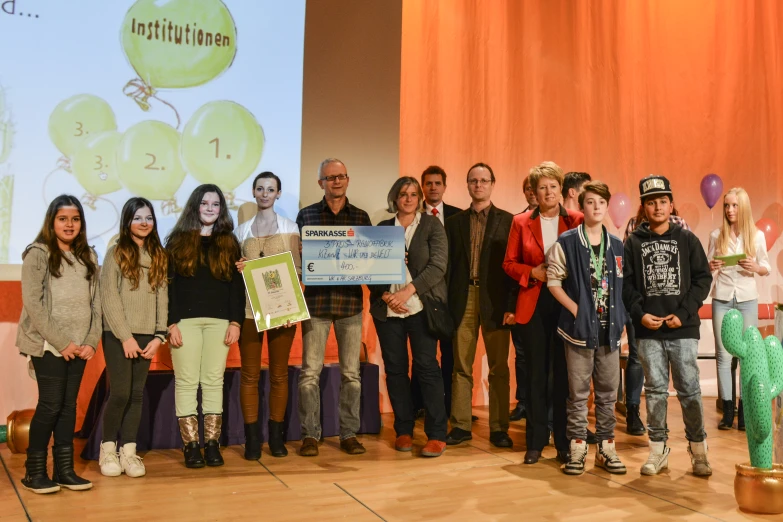 a group of children holding a large check from a young man