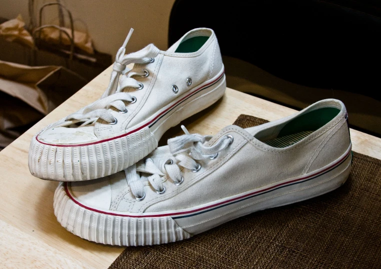 pair of white shoes sitting on a desk with paper on it