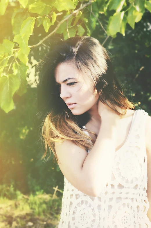 a woman is standing under a tree in front of green leaves